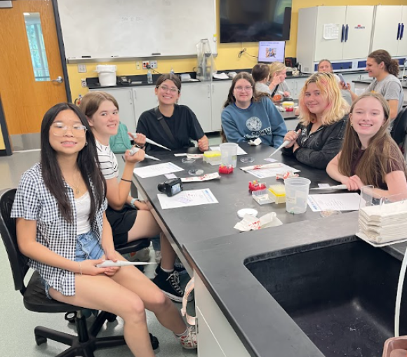 students around a table in a classroom holding pipettes