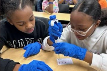 Two female students practicing using a micropipette
