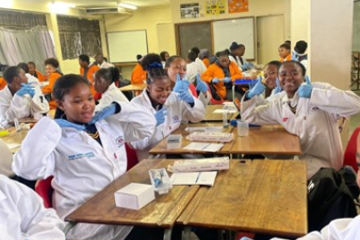 Student sin a science classroom waving to the camera