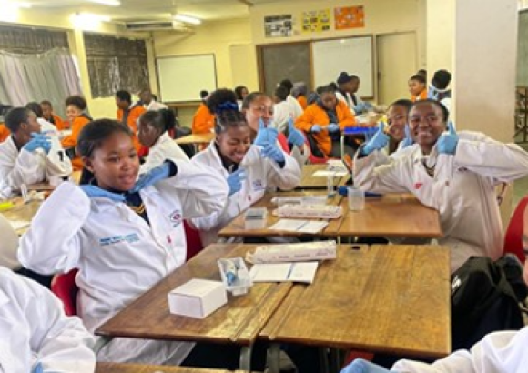 Student sin a science classroom waving to the camera